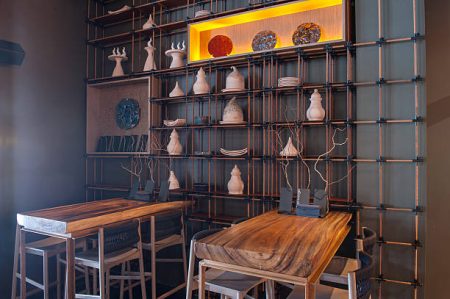 Elegant wooden tables and chairs in restaurant. Interesting utensil on the wall creates special decoration of interior