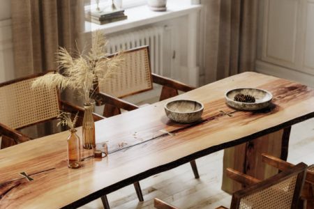 Wooden dining table and chairs. 3d rendering of rough edge plank dining table with glass vase and wooden utensils.